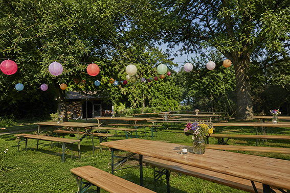 Garten mit dekorierten Bierbänken und Lampions im Sommer
